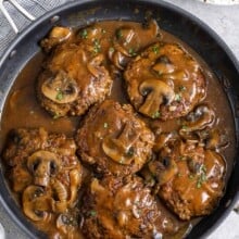 salisbury steak in a skillet next to mashed potatoes