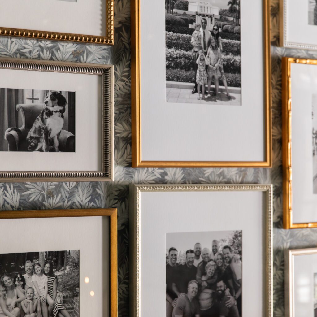 A close-up of a gallery wall of antique gold Framebridge frames filled with B&W photos of family