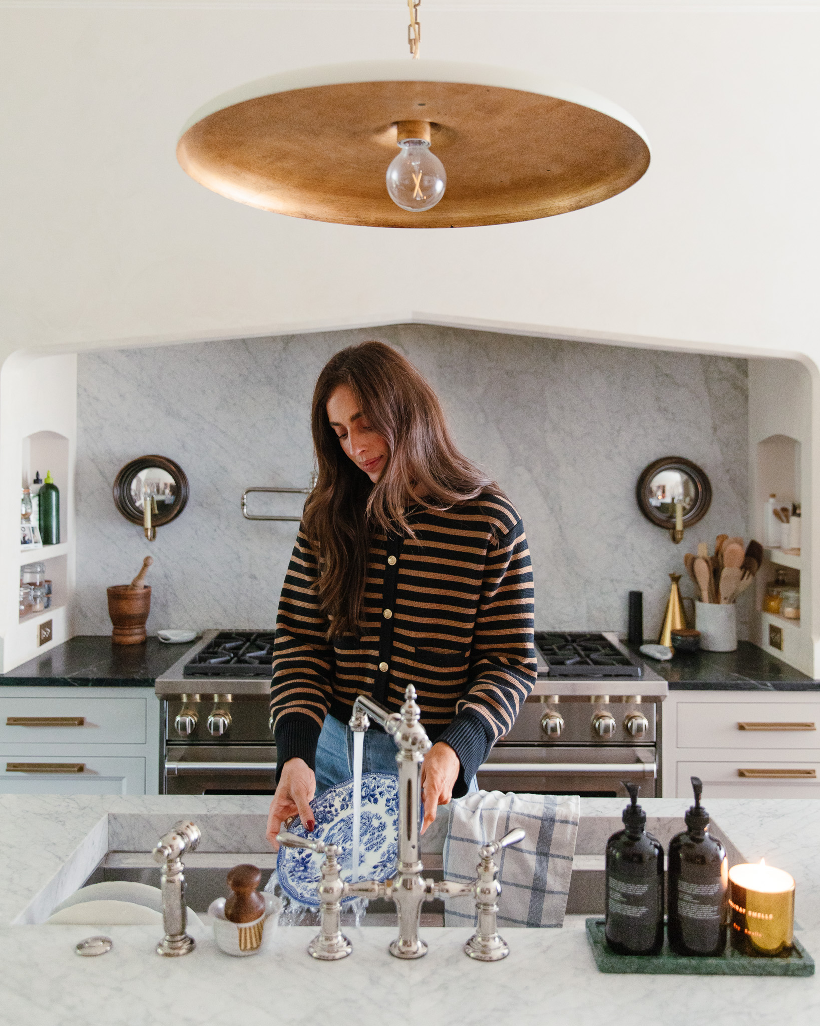 Julia rinsing a blue and white plate at the kitchen sink