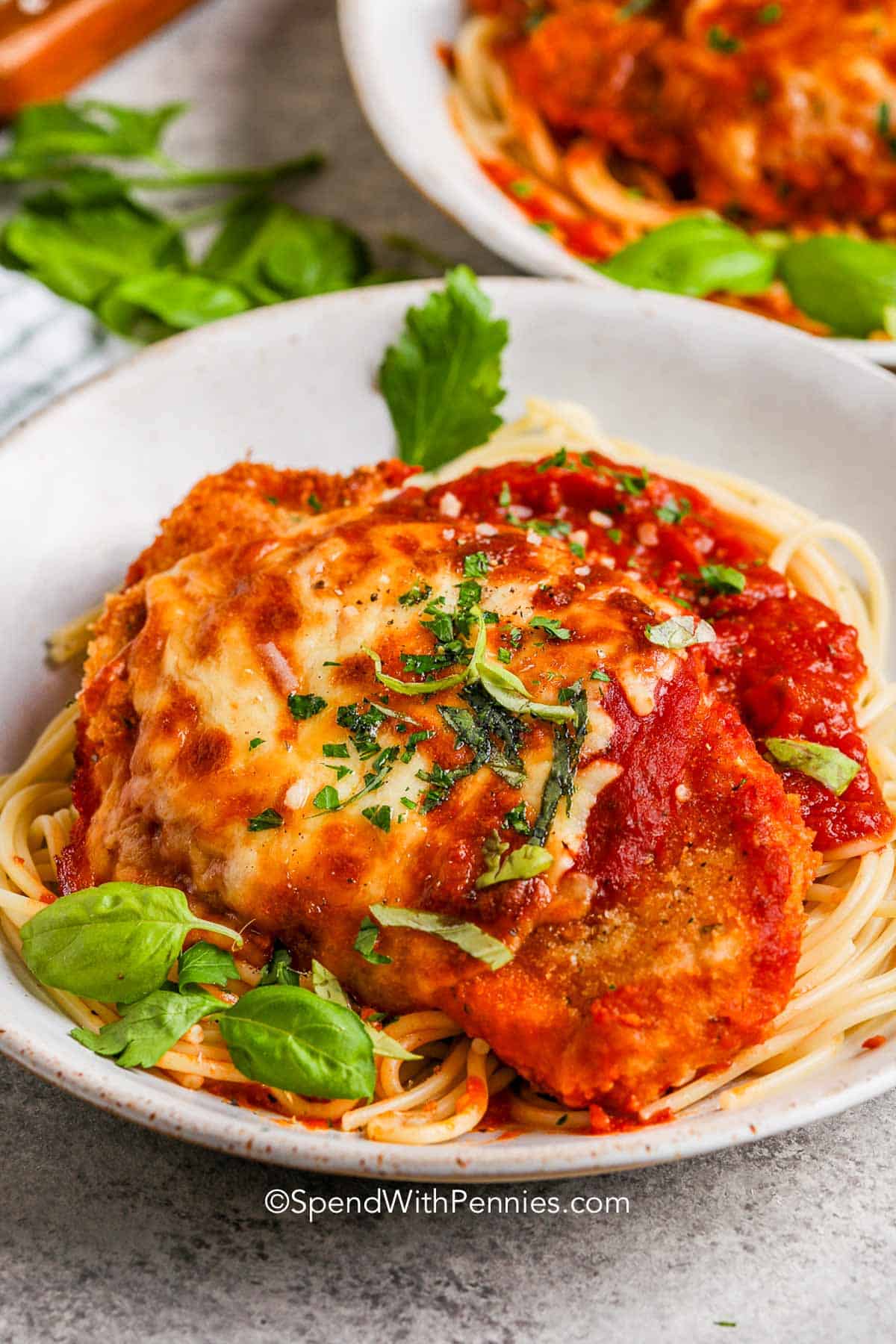 a bowl of spaghetti topped with baked chicken parmesan