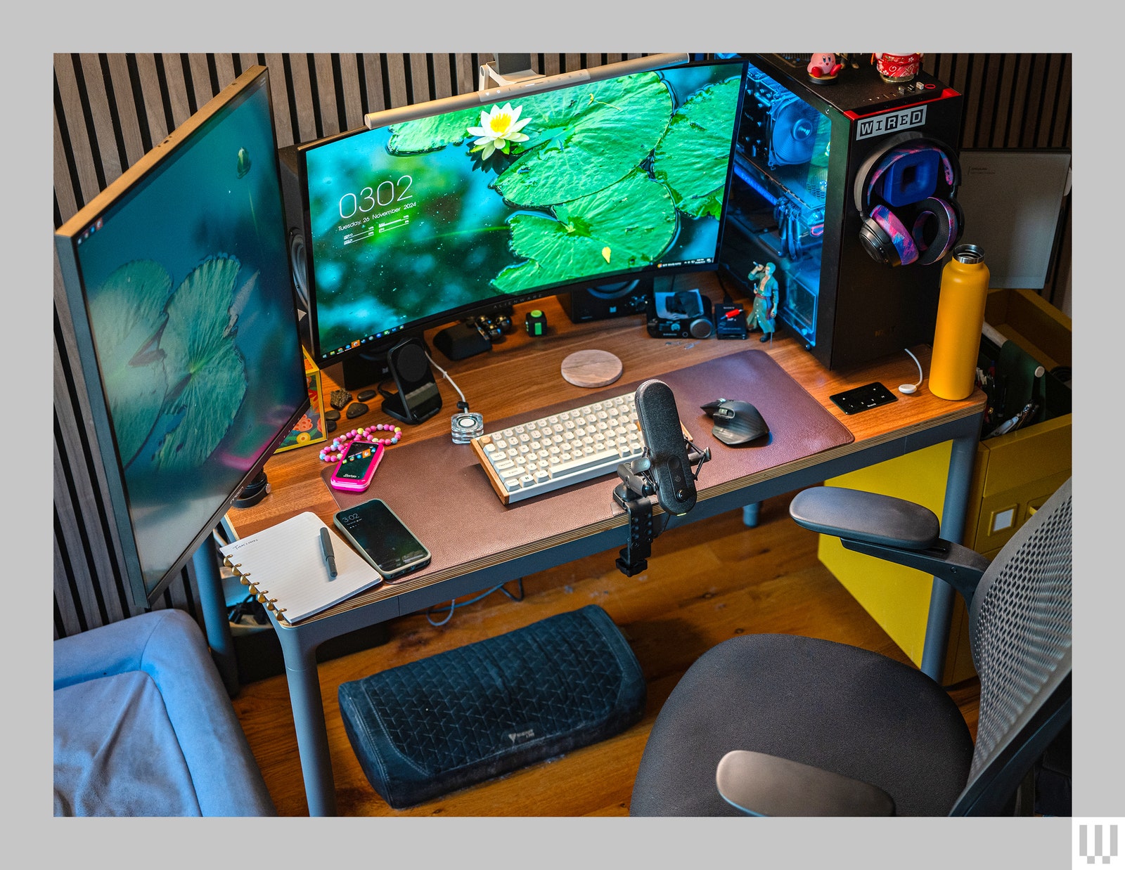 Front view of Branch Four Leg Standing Desk with computer monitors keyboard microphone and other work items on top