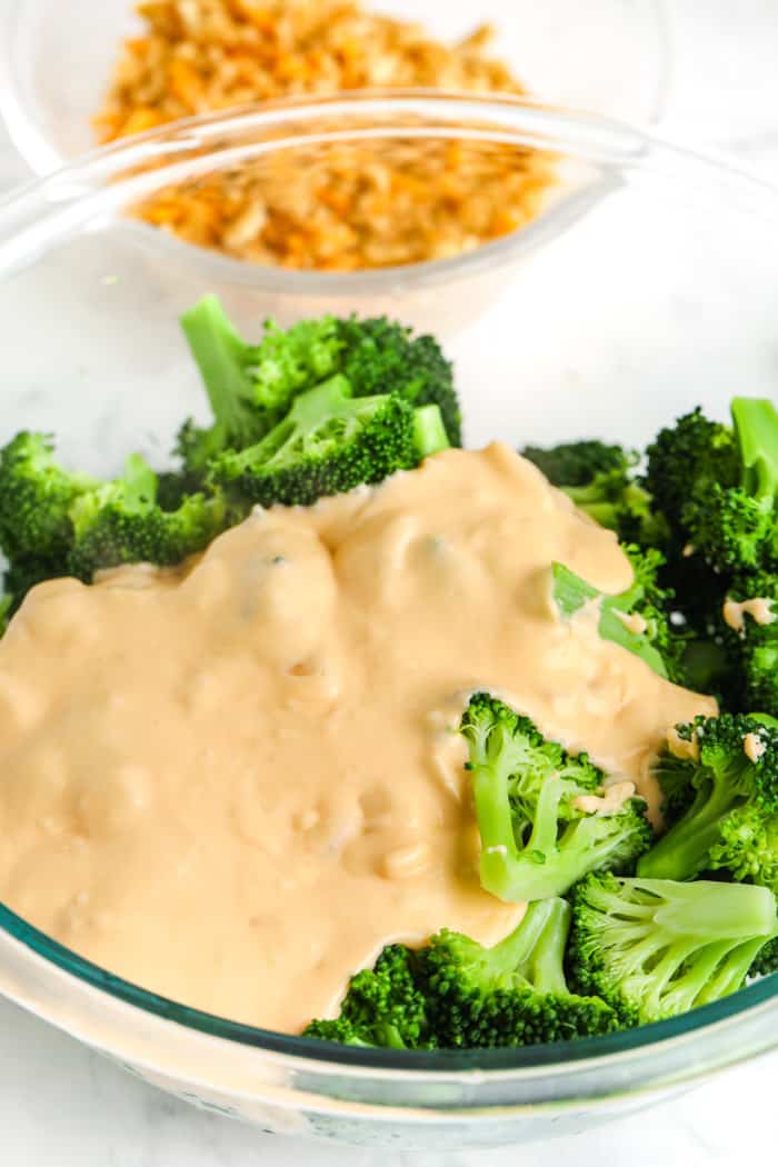 pouring cheese over broccoli to make Cheesy Broccoli Casserole