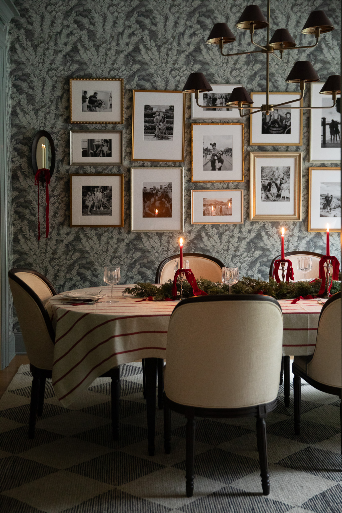 A cozy family dining room tablescape with lit red candles in gold candlesticks on a red-and-cream striped tablecloth