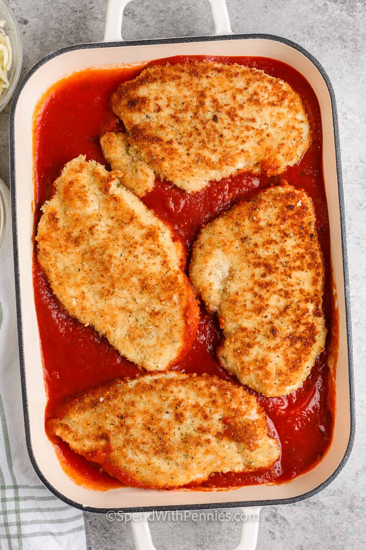 adding cooked chicken to pan with sauce to make Easy Chicken Parmesan