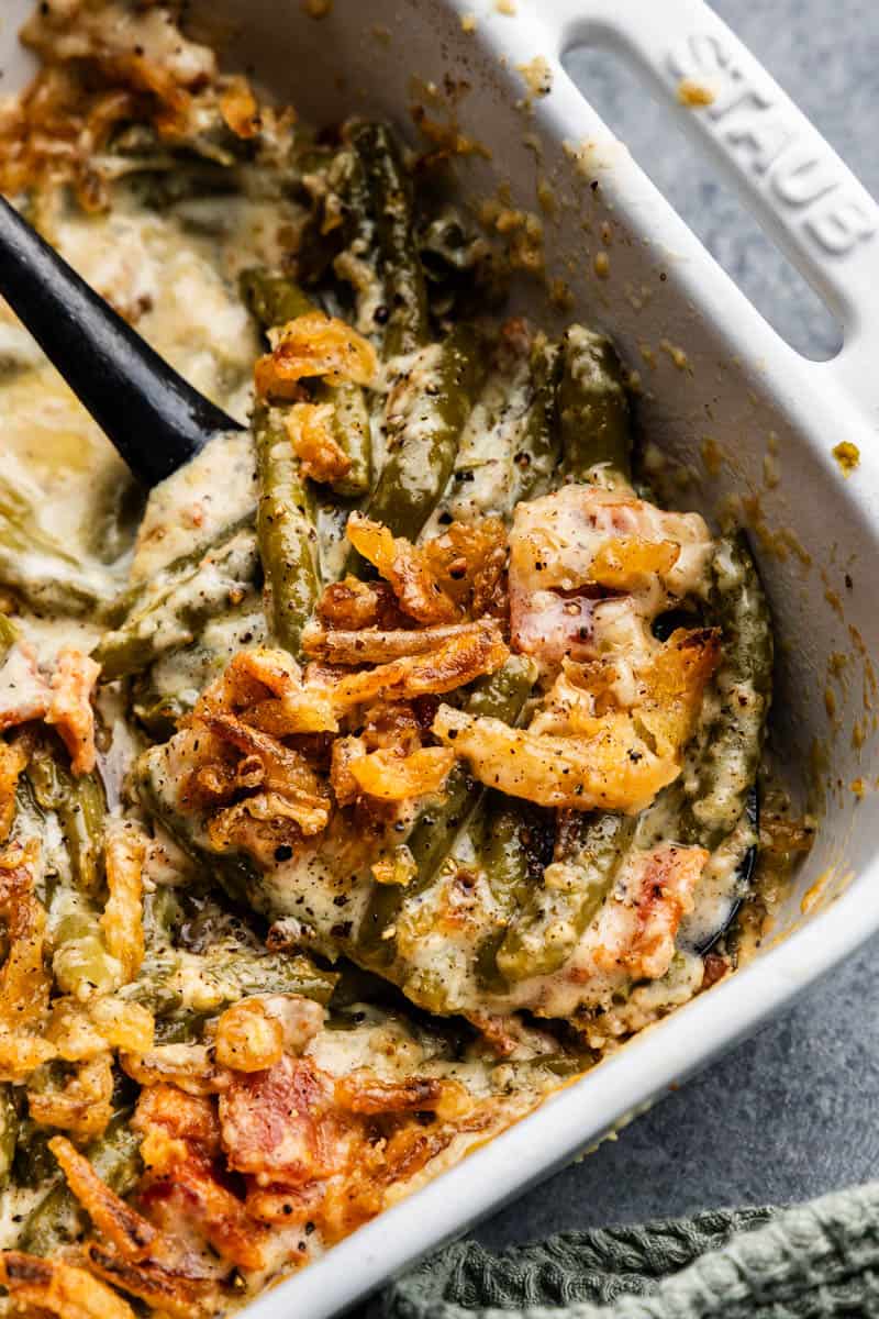 A pan of green bean casserole with a spatula in the pan ready to dish out the next serving.