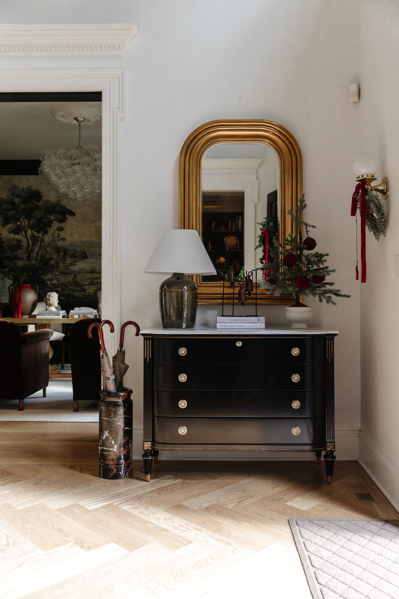 A front entry at Christmas with a small tree and burgundy red velvet ribbon and ornaments