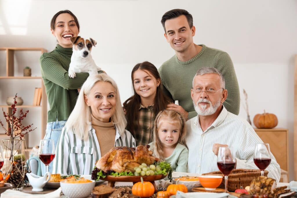 Happy Family Having Dinner At Festive Table On Thanksgiving Day