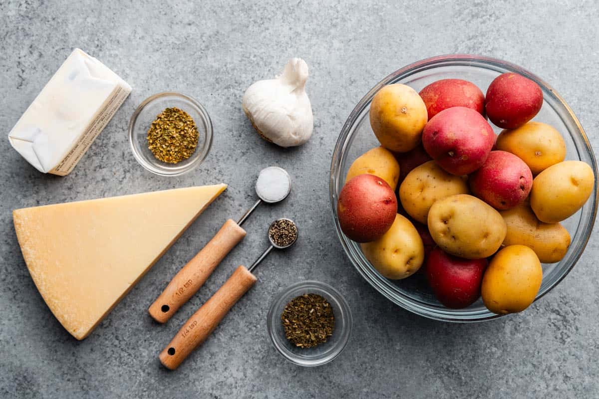 An overhead view of raw potatoes next to wet and dry ingredients needed to make garlic bread smashed potatoes.