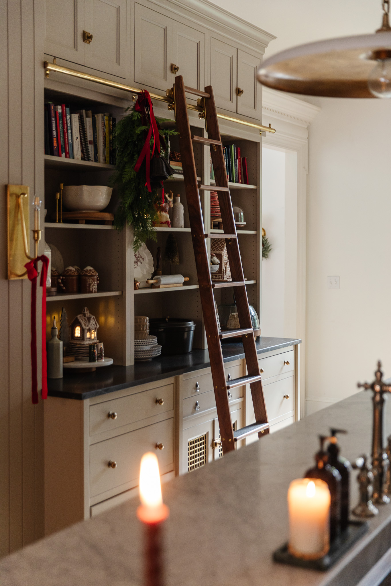 A kitchen decorated for Christmas with red ribbons, a green wreath, and ceramic gingerbread houses