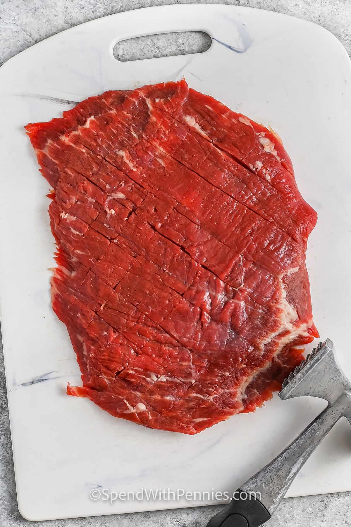 flattening flank steak with a hammer to make London Broil