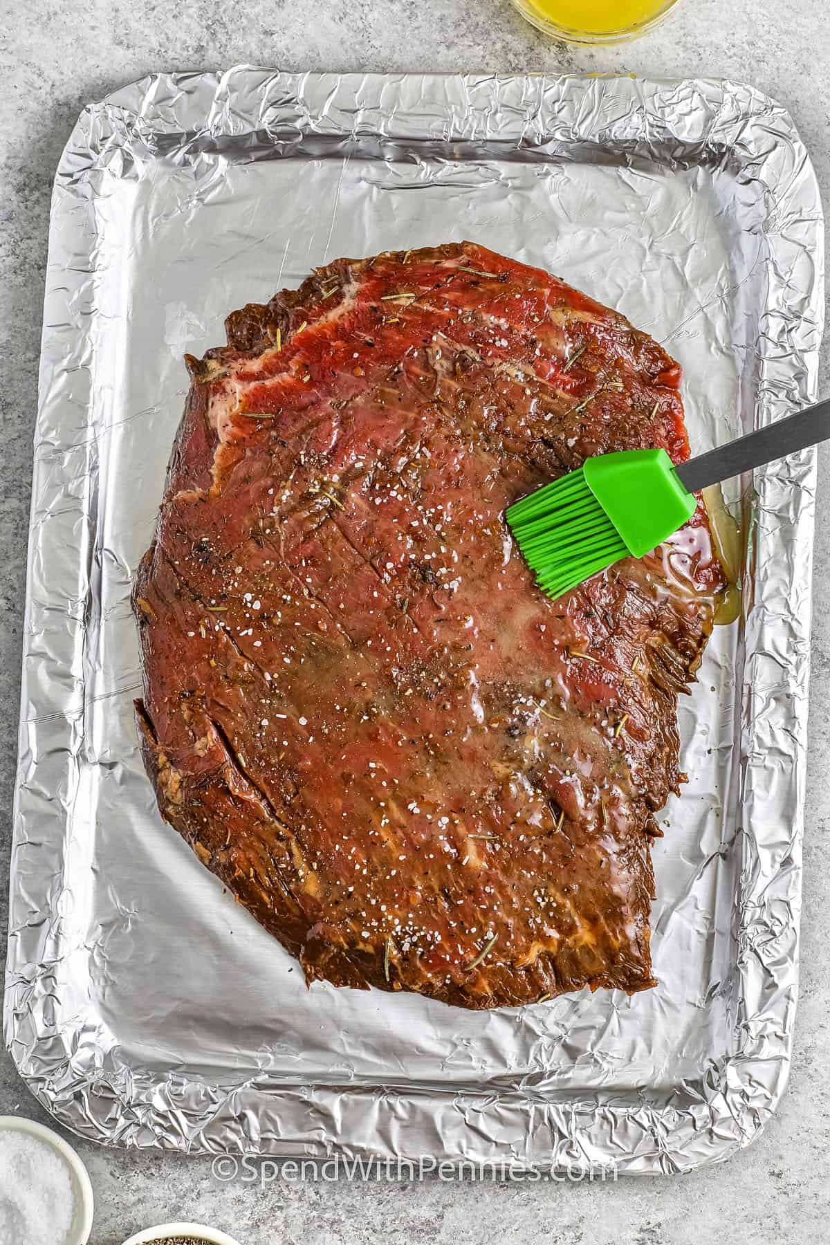 brushing sauce over flank steak to make London Broil