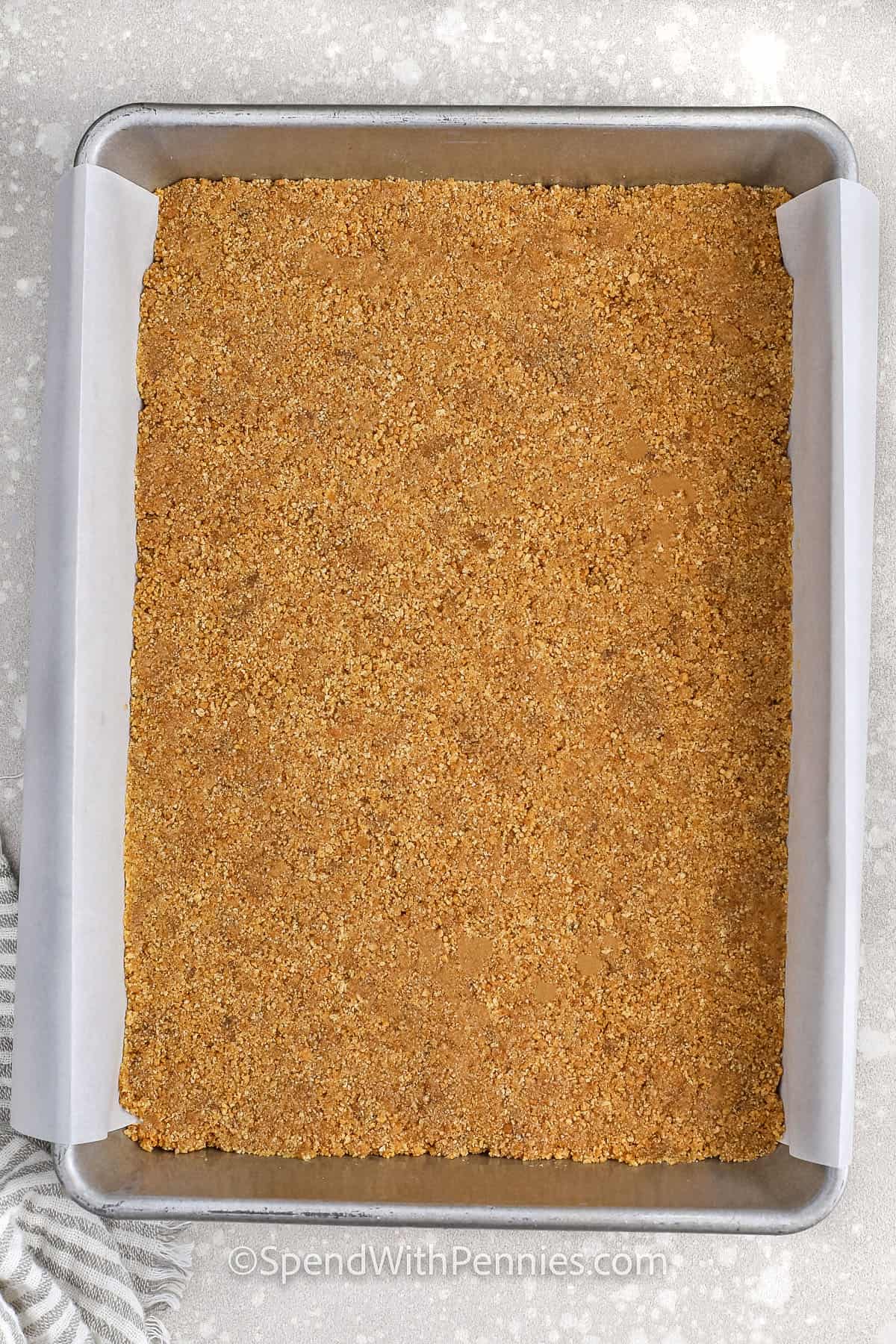 adding graham cracker crust to pan to make Pumpkin Cheesecake Bars