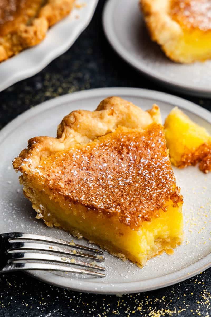 A slice of chess pie on a plate. A fork is resting on the plate as the first bite has been taken.