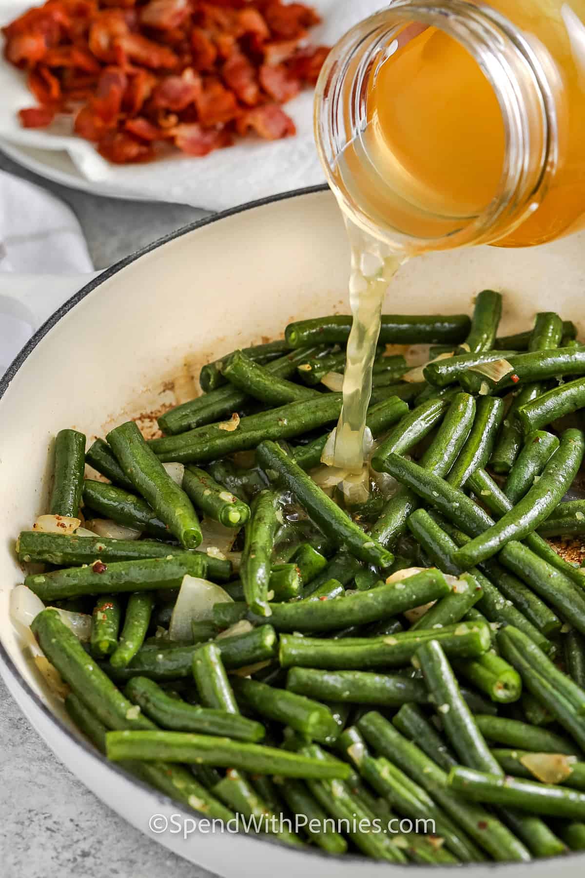 adding broth to green beans and onion mixture to make Southern Green Beans