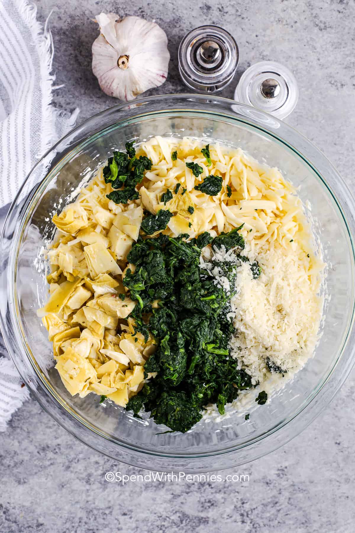 adding cheese , spinach and artichokes to cheese mixture to make Spinach Artichoke Dip