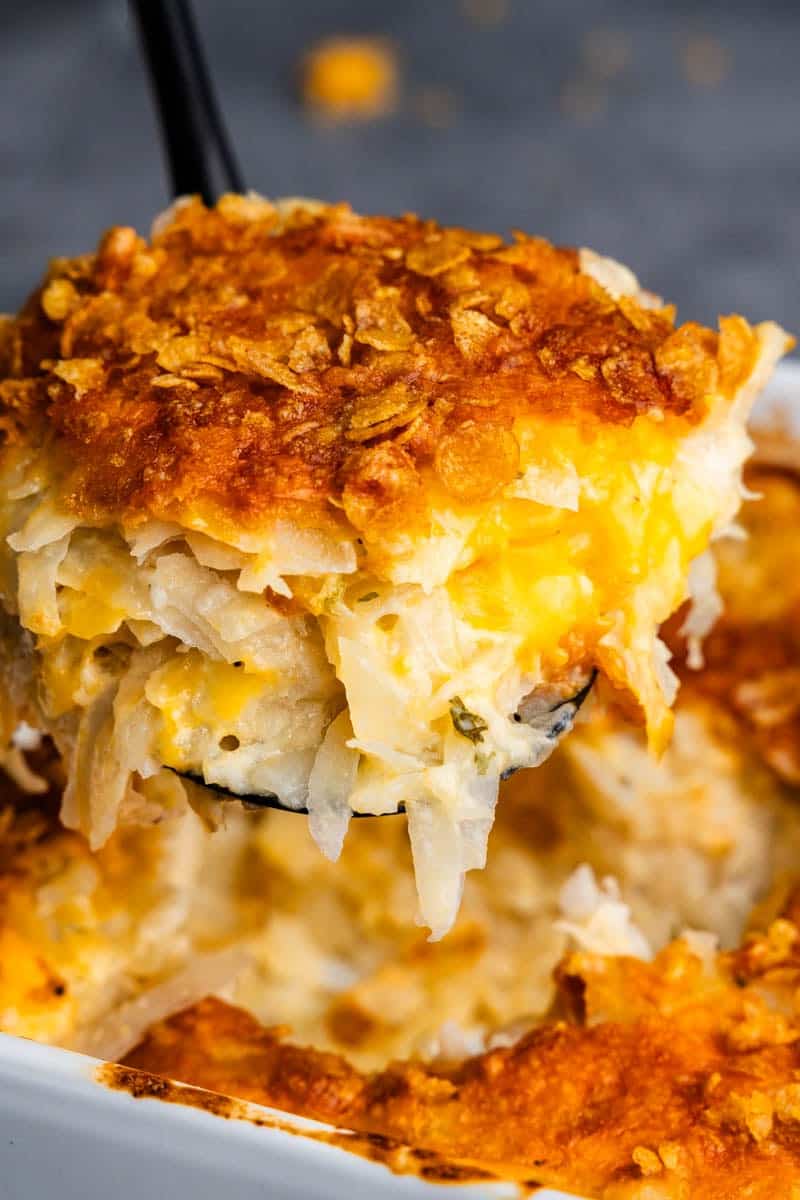 A helping of funeral potatoes being dished from the pan.