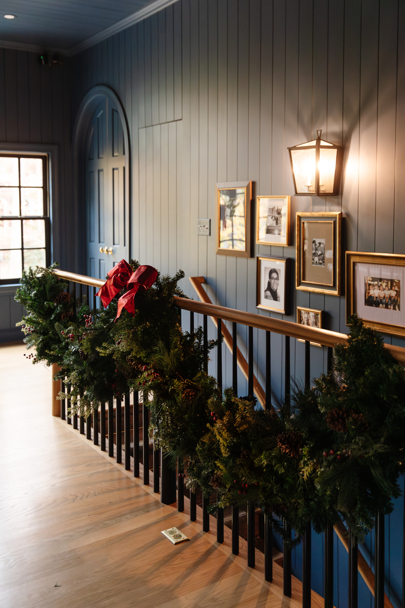 A large swooping swag garland and shiny bow on the walkway handrail