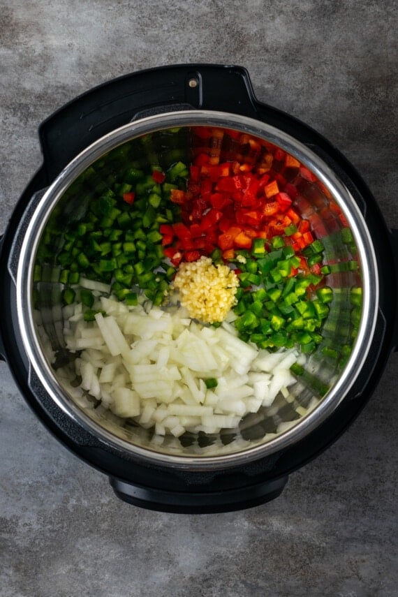 Diced peppers, onions, chilies, and garlic combined in the instant pot.