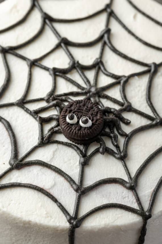 Close up of a mini Oreo decorated to look like a spider in the center of a piped frosting web.