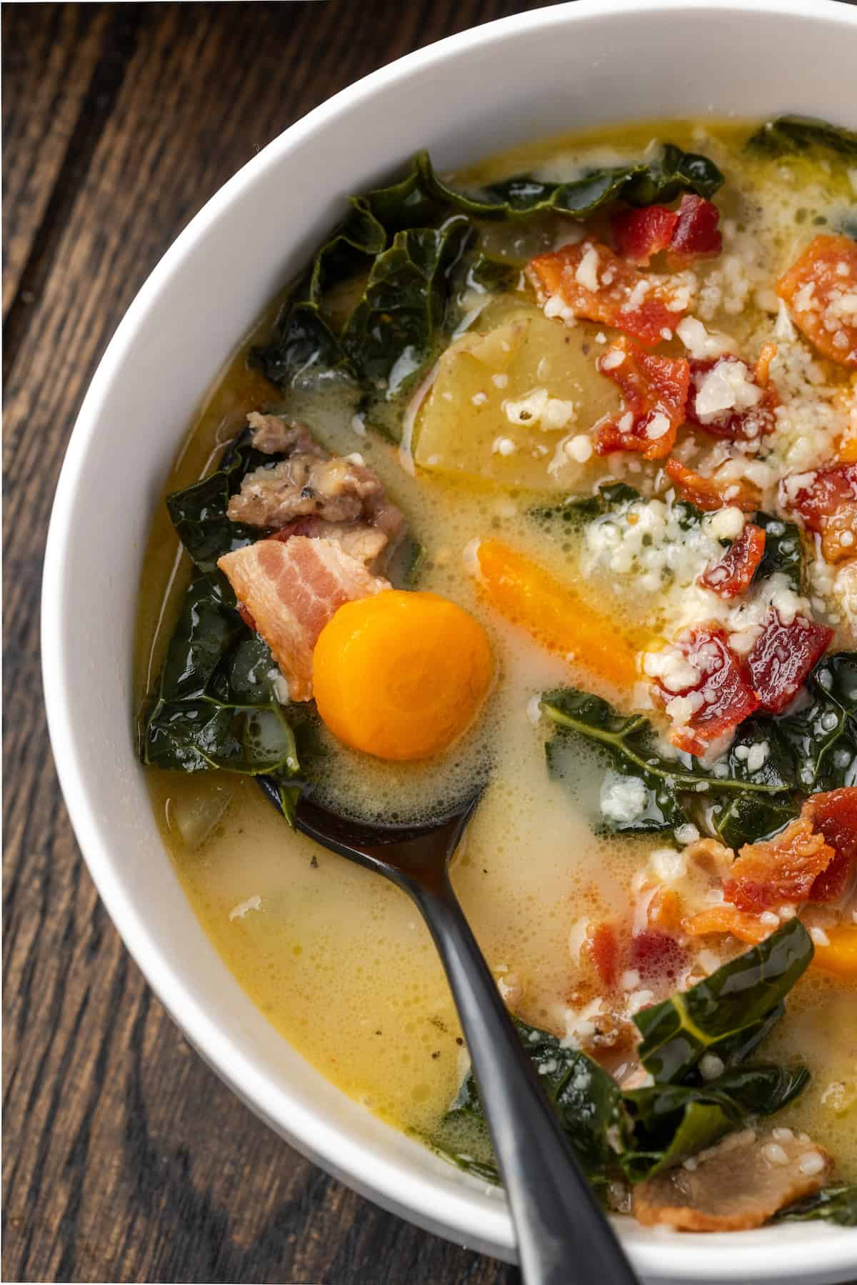 Overhead close up view of a spoon resting in a bowl of Zuppa Toscana.