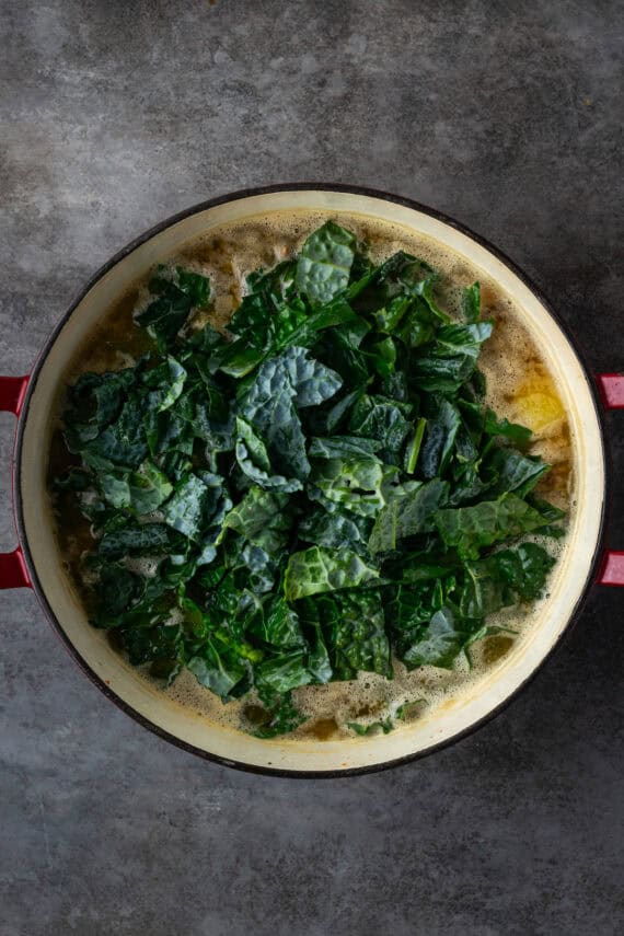 Kale added to a pot of soup.