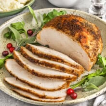 turkey breast on a plate with garnish for Crockpot Turkey Breast