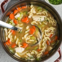 a ladle in a pot of turkey noodle soup