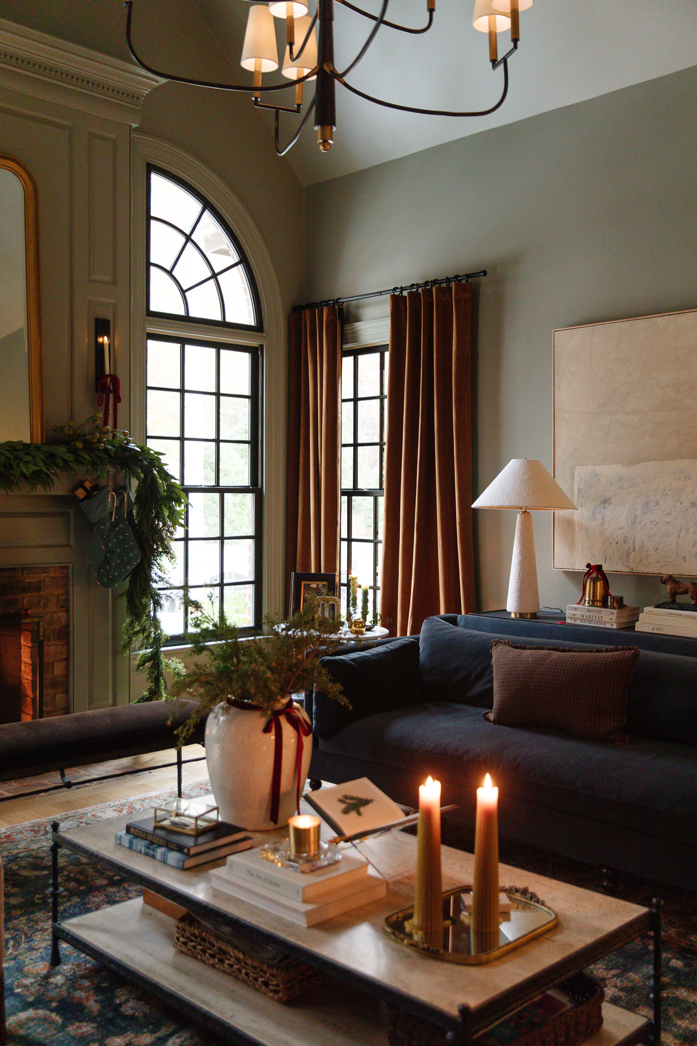 A cozy living room with a reflective mirror tray and two tall wide taper candles on top