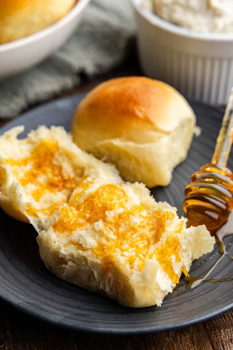 potato roll with honey drizzled on it on a black plate