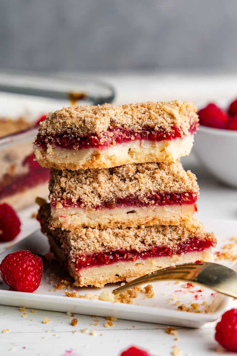 freshly made raspberry streusel dessert bars stacked on white plate