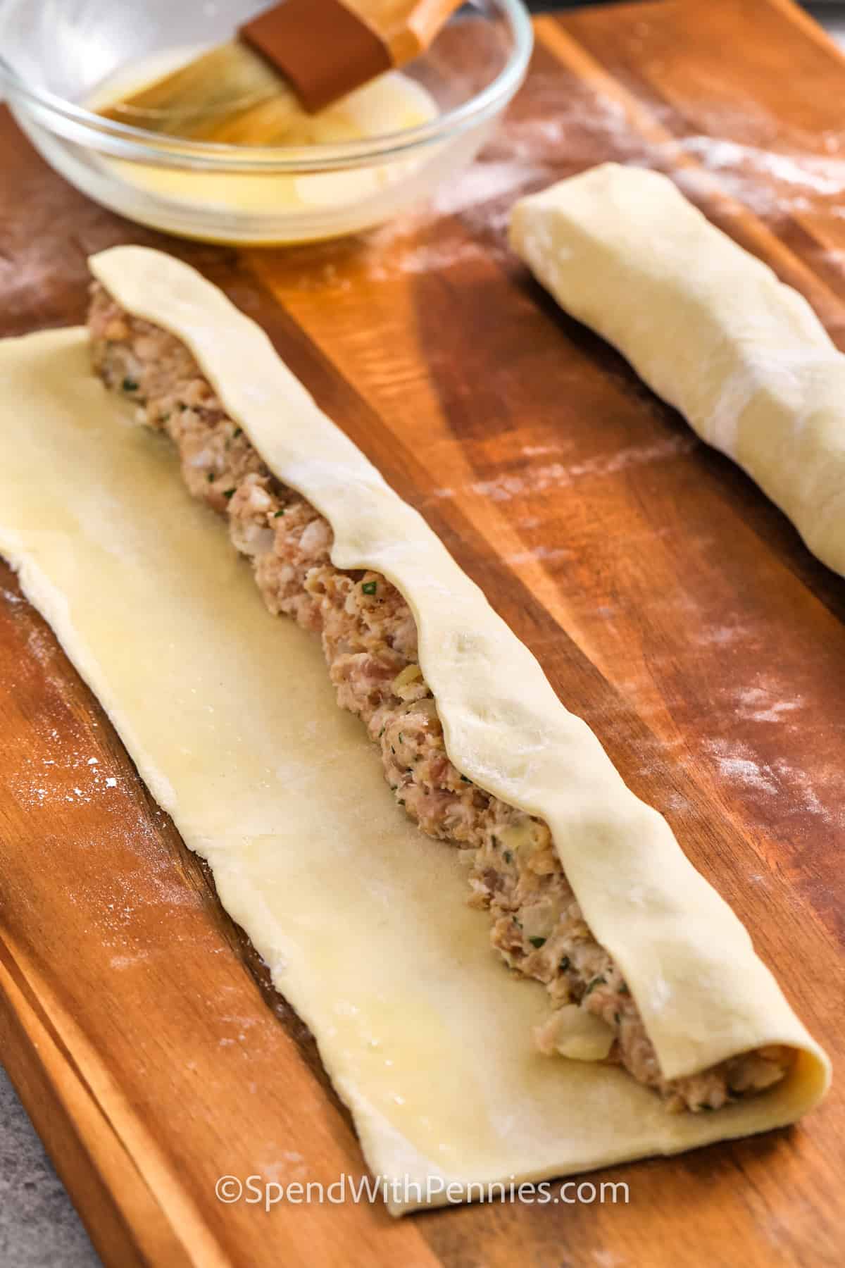 rolling Sausage Rolls on a wooden cutting board