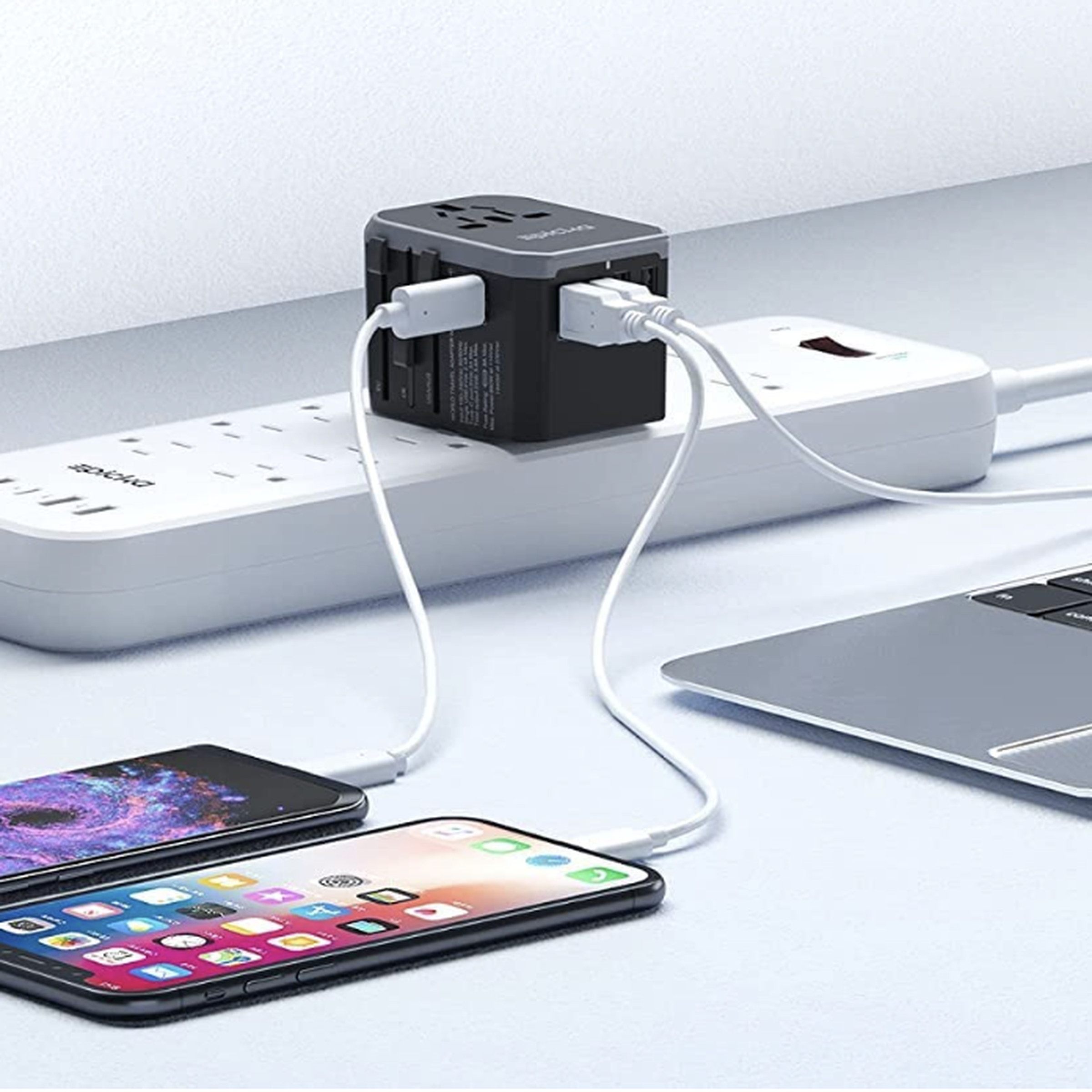 Travel adaptor on power strip connected to phones and laptop.