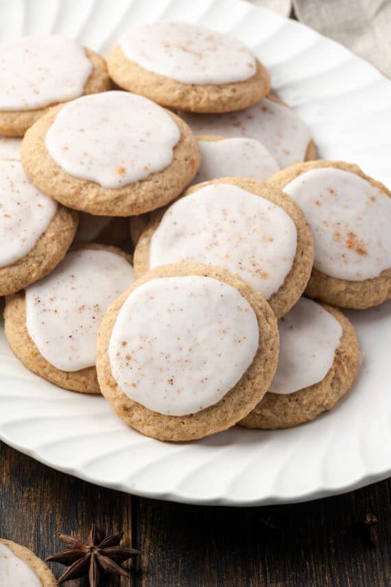 Frosted chai sugar cookies piled on a white scalloped platter.