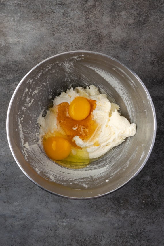 Eggs added to creamed butter and sugar in a metal mixing bowl.