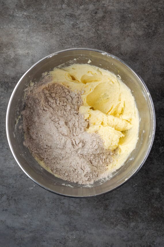 Dry ingredients added to wet cookie dough in a mixing bowl.