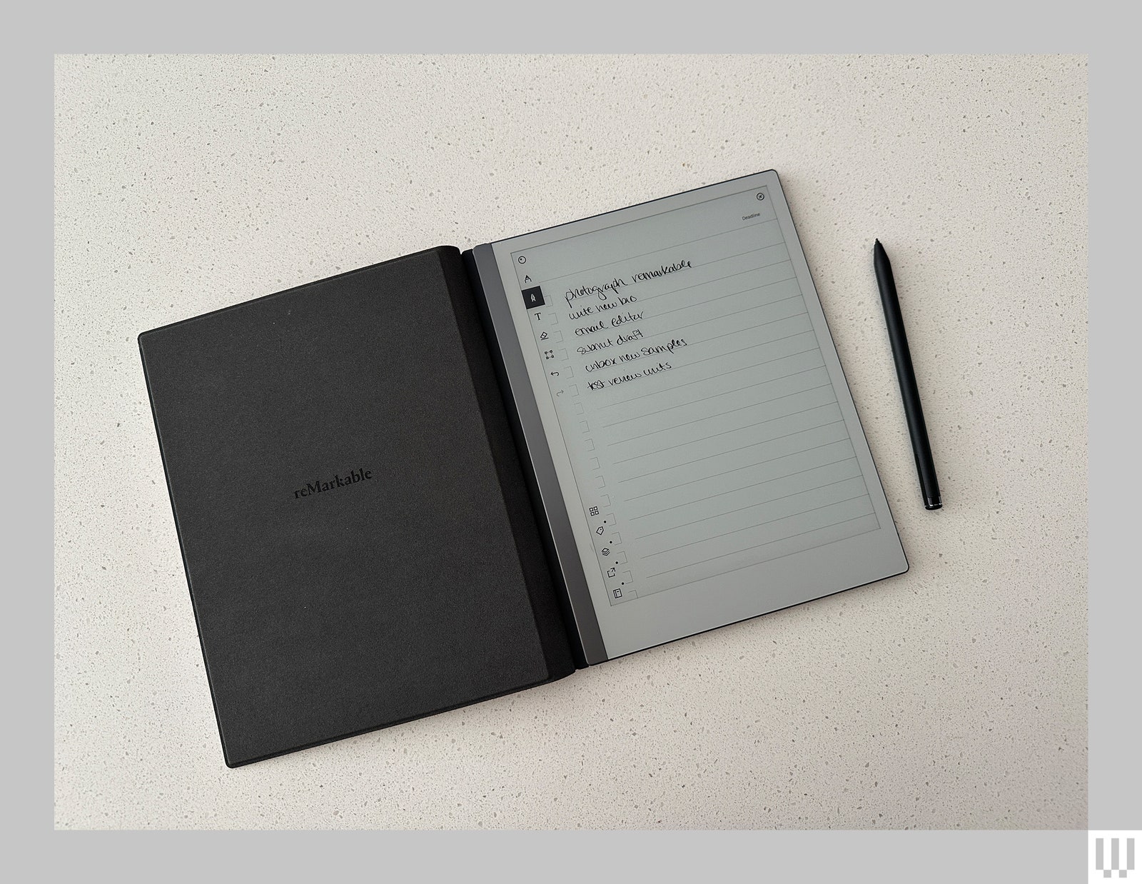 Digital notebook open and flat on a white surface with the digital pen beside it