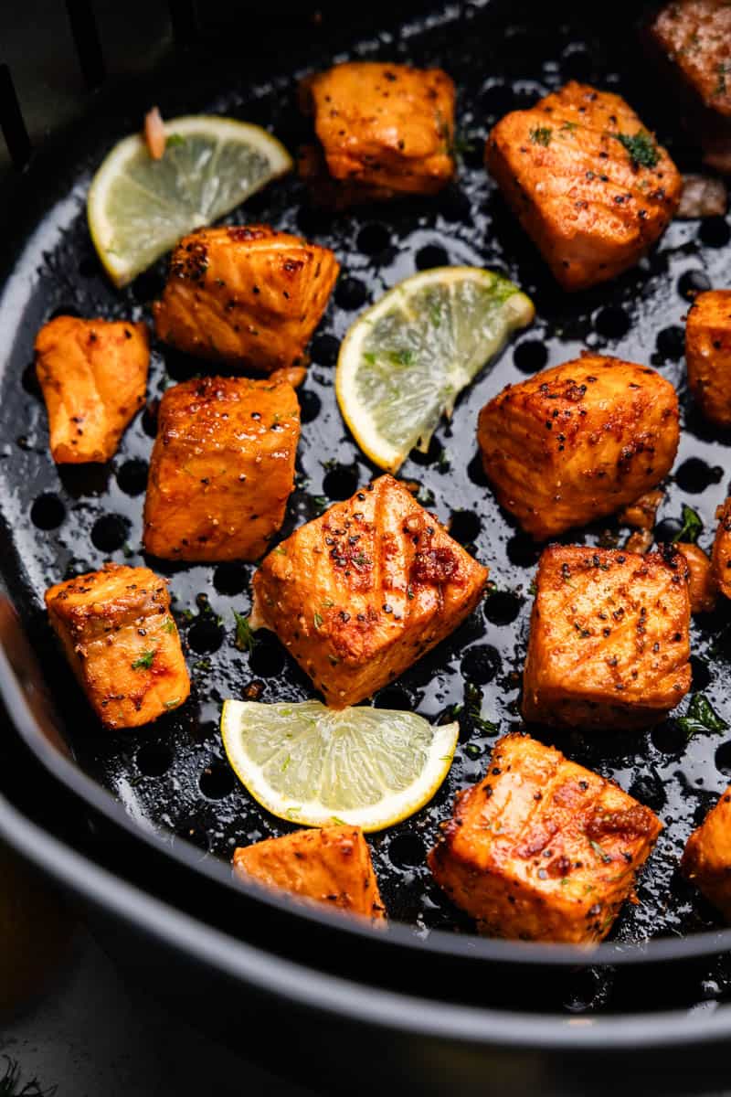 A close up view of salmon bites in the basket of an air fryer.