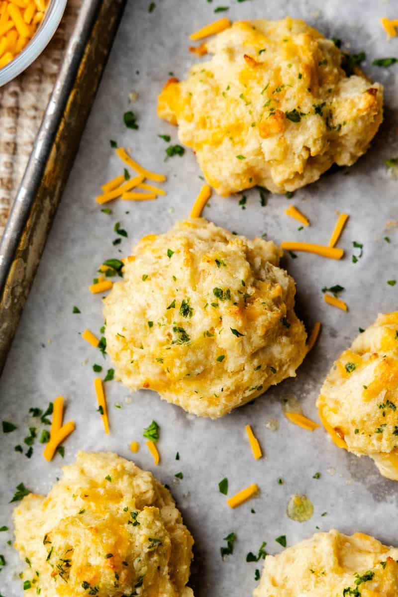 A close up view of cheddar bay biscuits on a baking sheet.