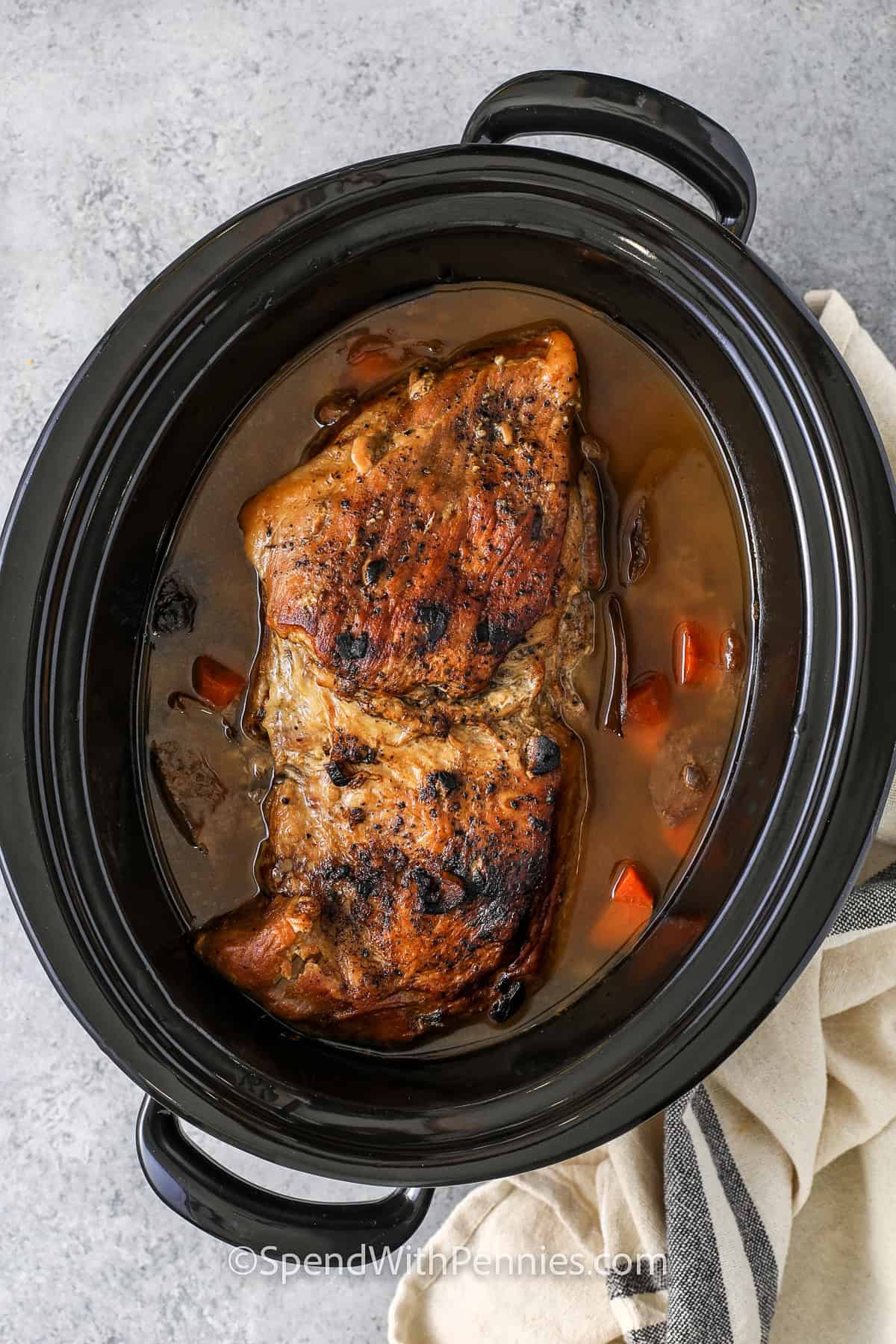 cooked Crock Pot Pork Roast with carrots and broth in the pot