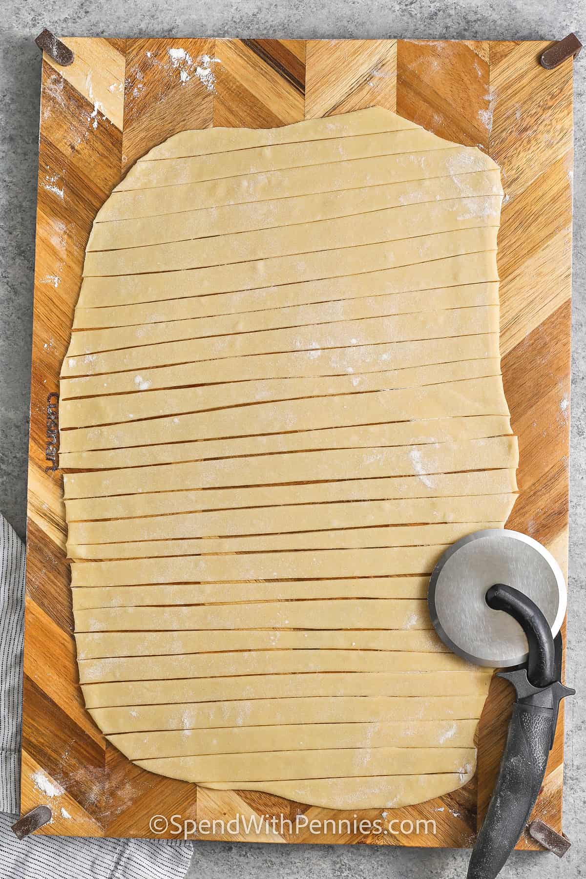 slicing dough to make Egg Noodles