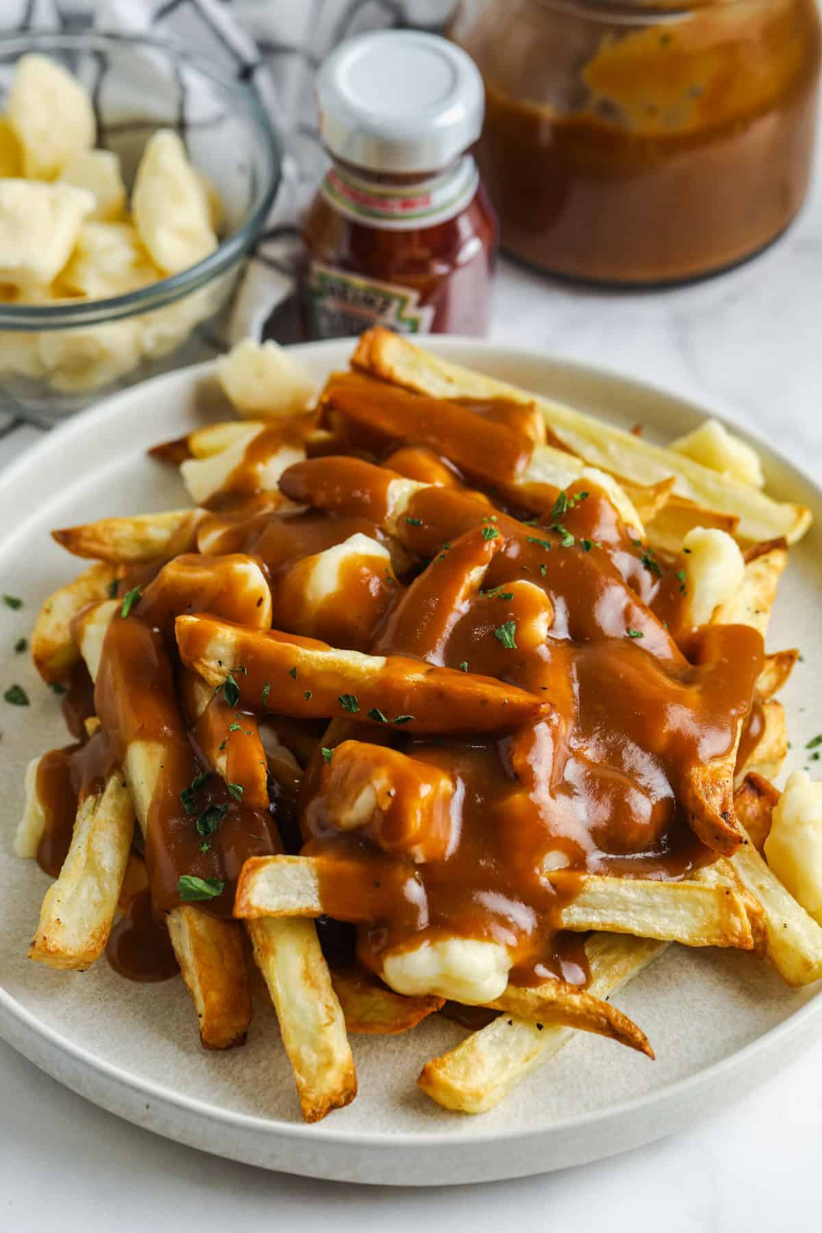 A plate of poutine with ketchup next to it