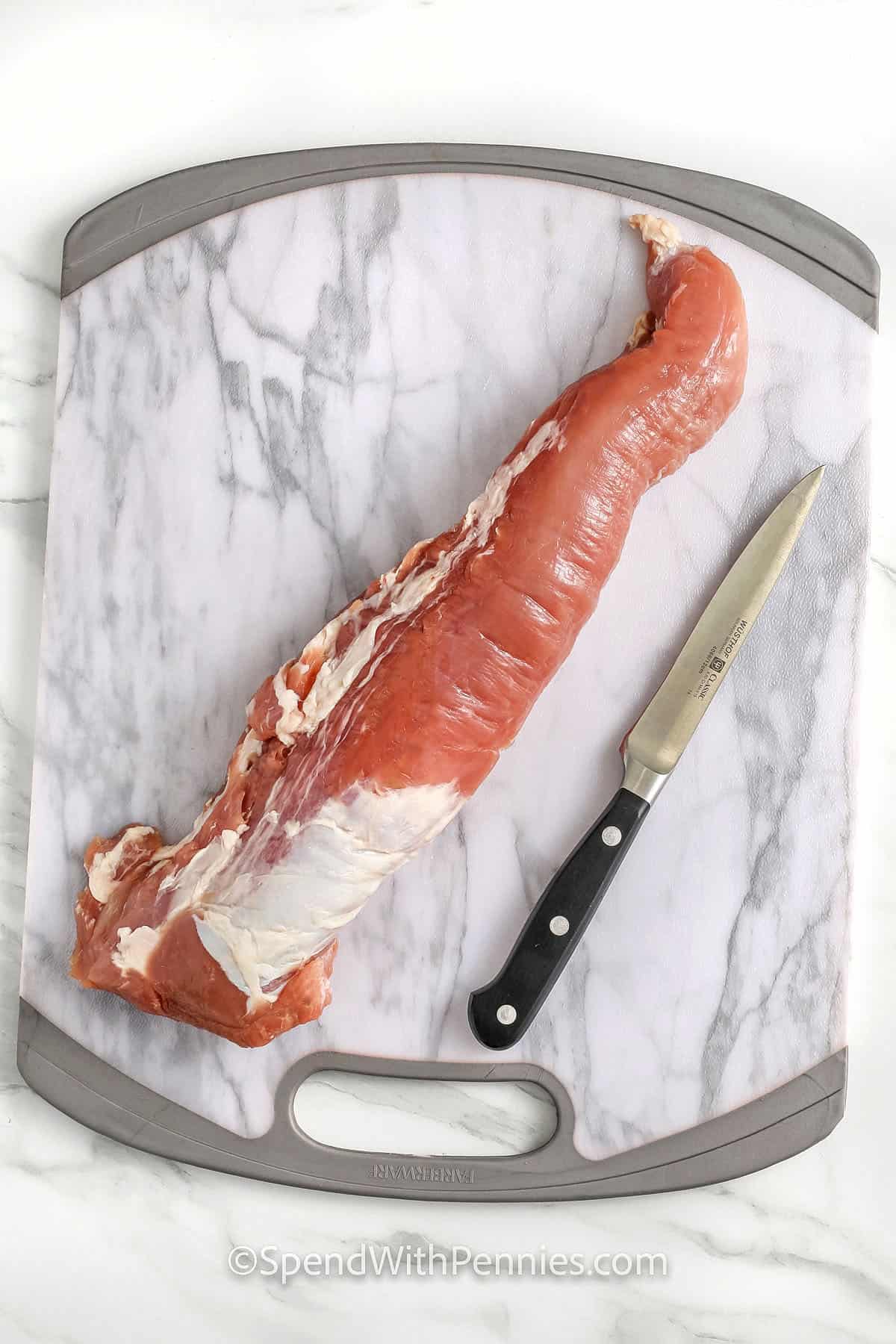 pork on a cutting board with a knife to show How to Remove Silverskin from Pork Tenderloin