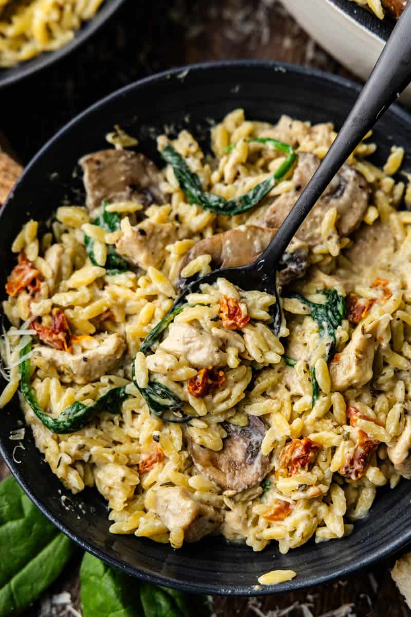 A silicone spatula scooping a helping of One Pot Italian Pasta Orzo out of pan.