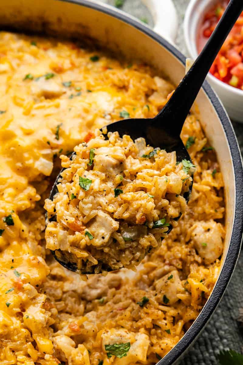 An overhead view of a spoonful of queso chicken and rice being scooped out of the pot.