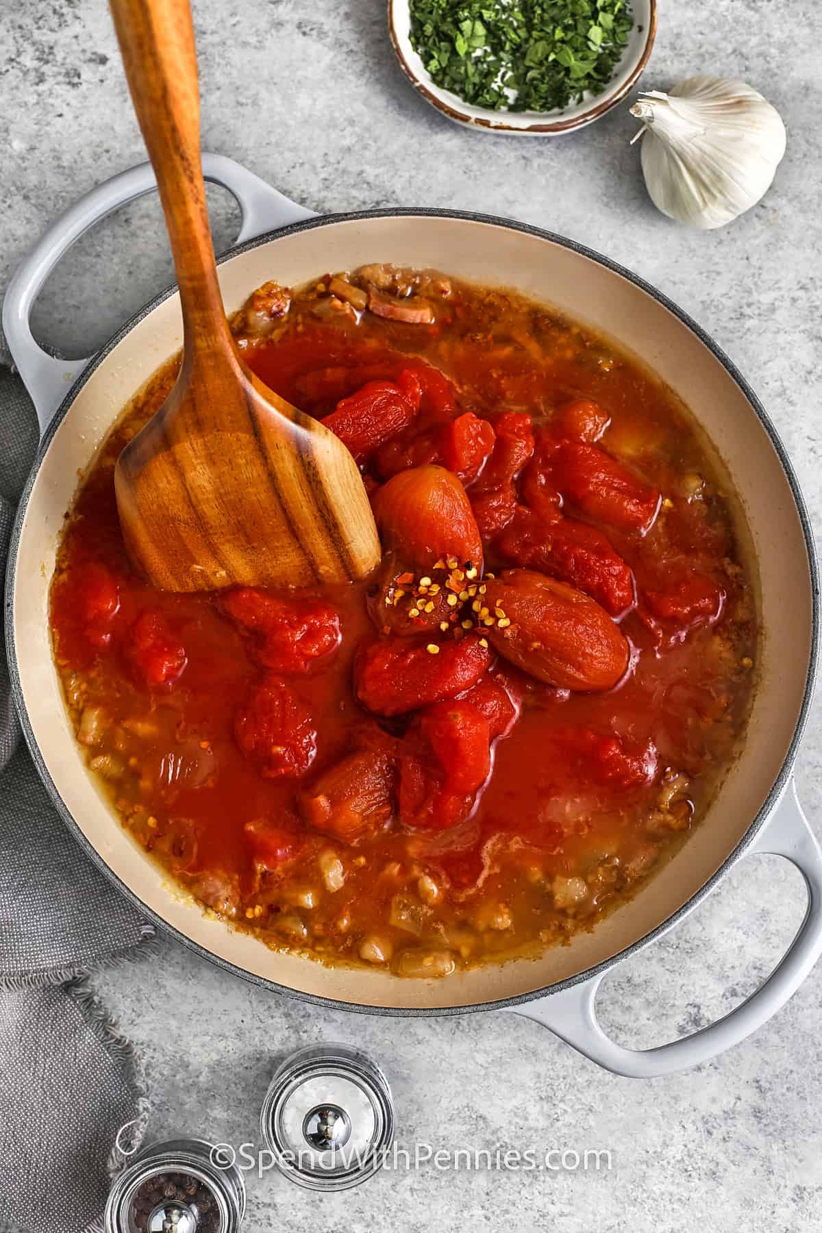 adding tomatoes and broth to pan to make Penne alla Vodka