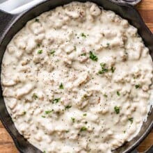 a skillet of sausage gravy on a wood board