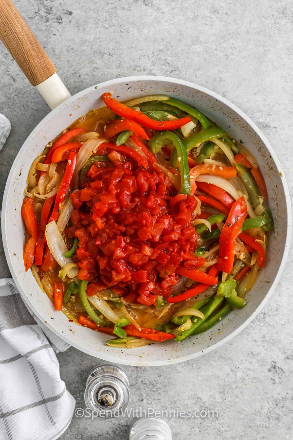 adding tomatoes to pepeprs mixture in pan to make Sausage and Peppers