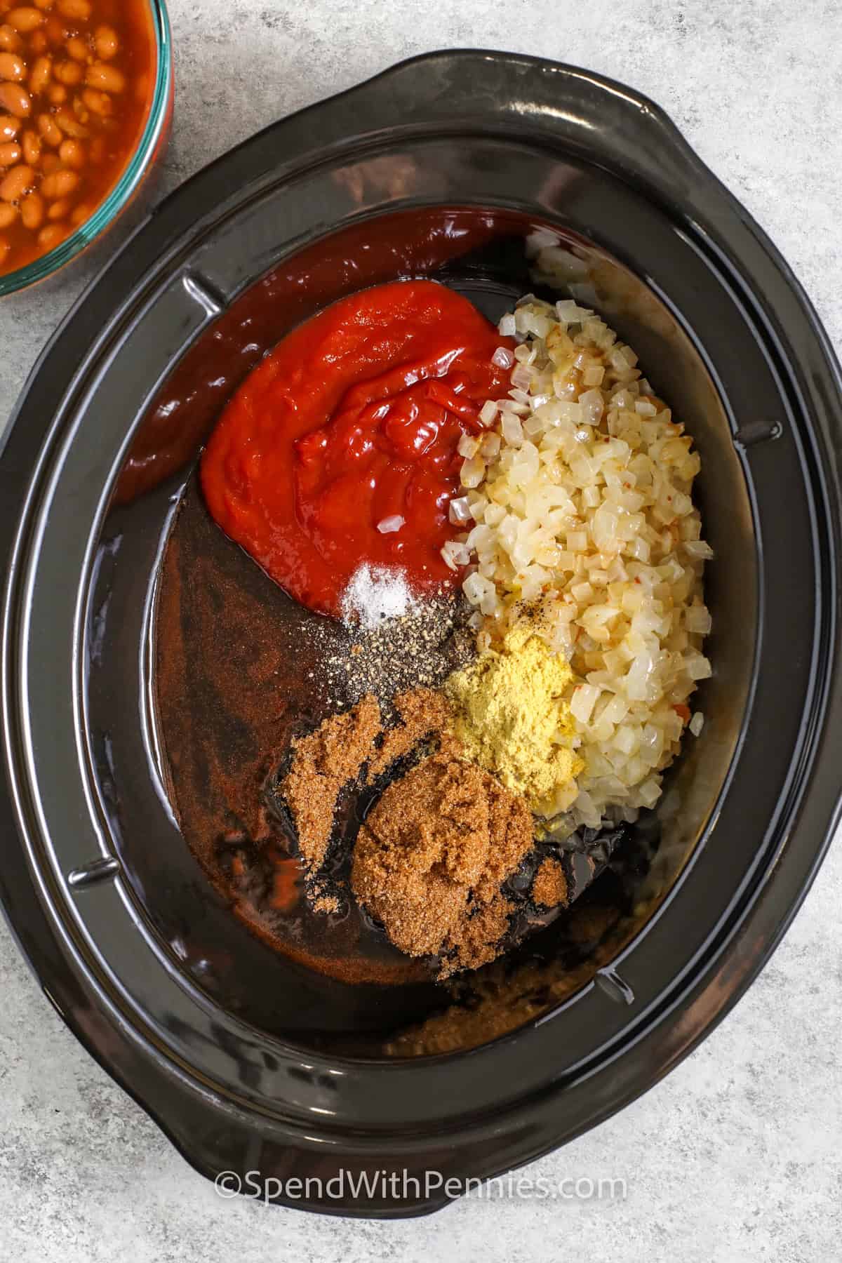 adding onions , ketchup and seasonings with brown sugar to pot to make Slow Cooker Baked Beans