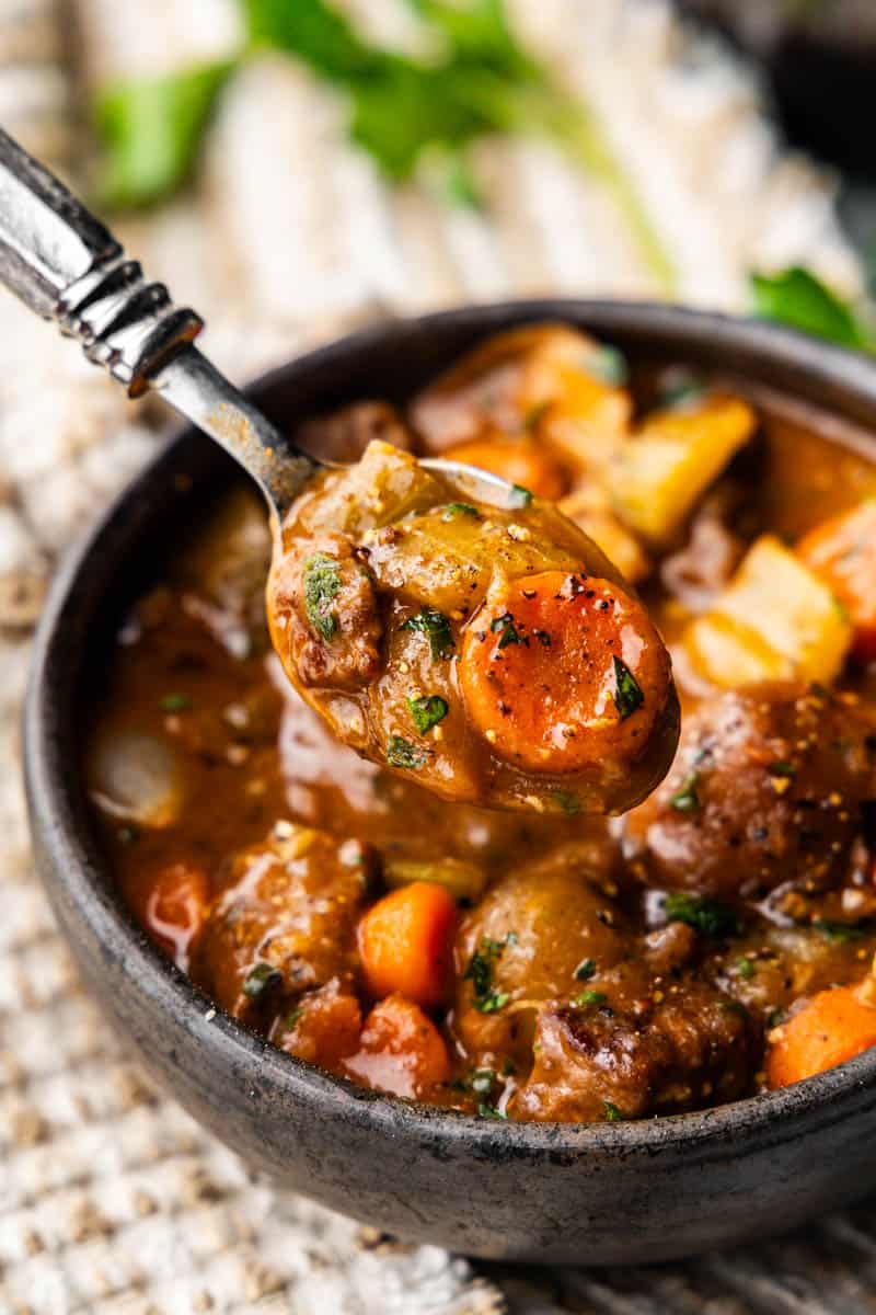 spoon full of slow cooker beef stew bite over a bowl