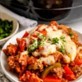 unstuffed peppers on a white plate topped with melted cheese and parsley